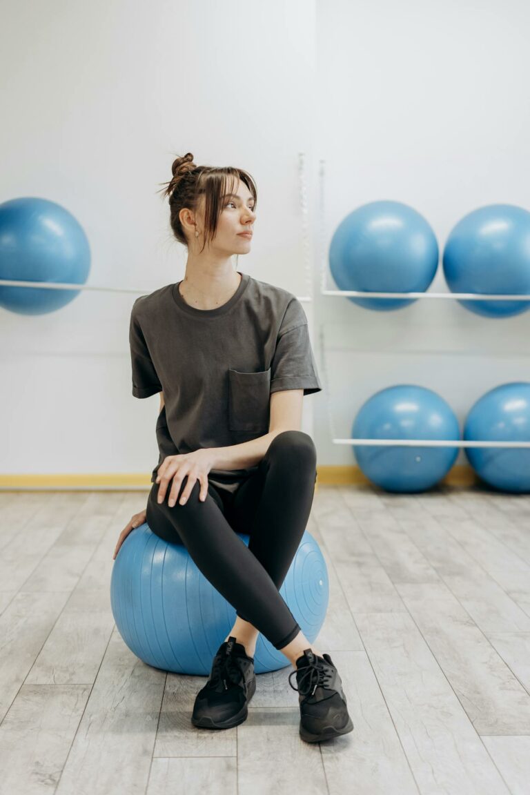 A woman sitting on a yoga ball indoors, promoting a healthy and mindful lifestyle.