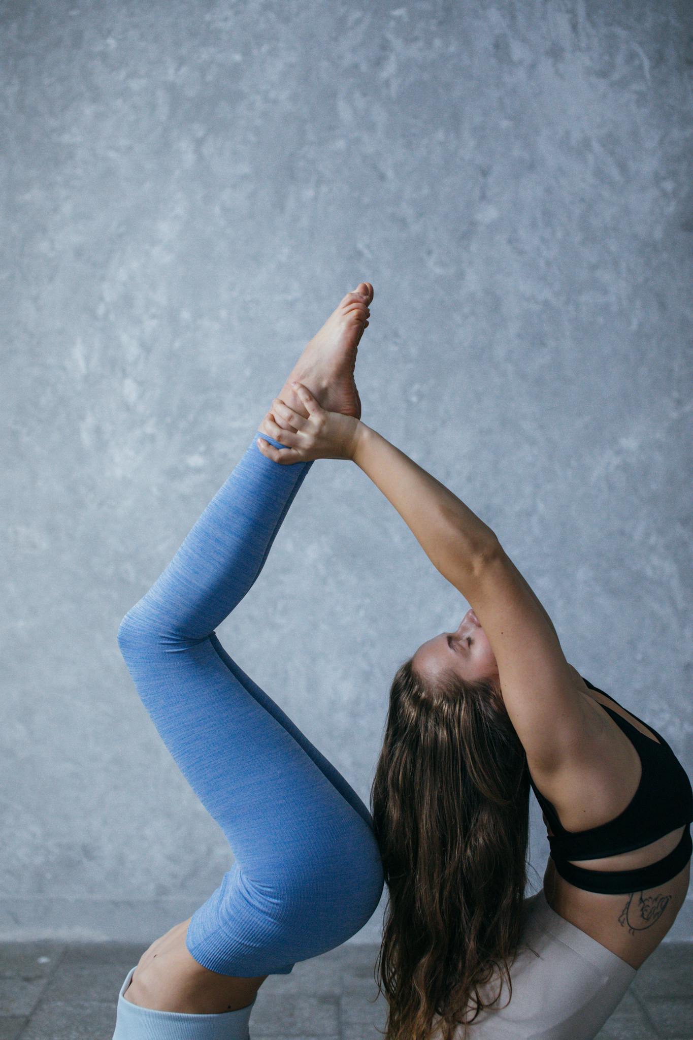 Adult woman performing yoga pose indoors, showcasing balance and flexibility for tranquility.