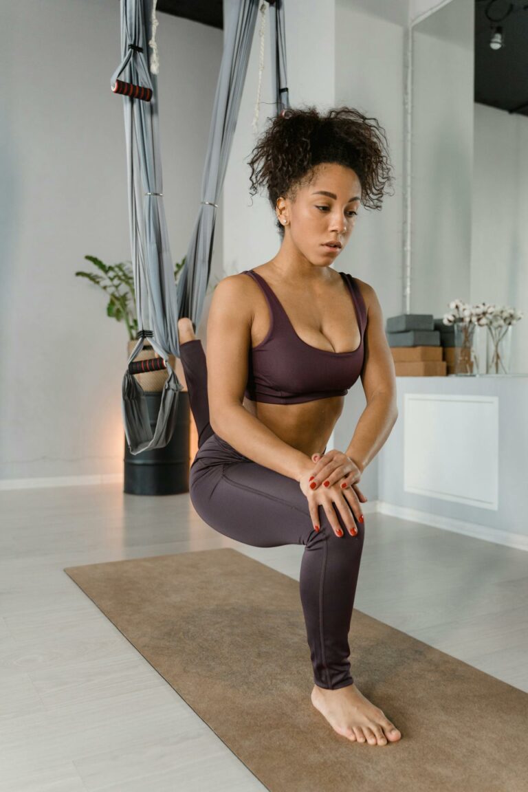 Young woman practicing aerial yoga in modern studio, focusing on flexibility and balance.